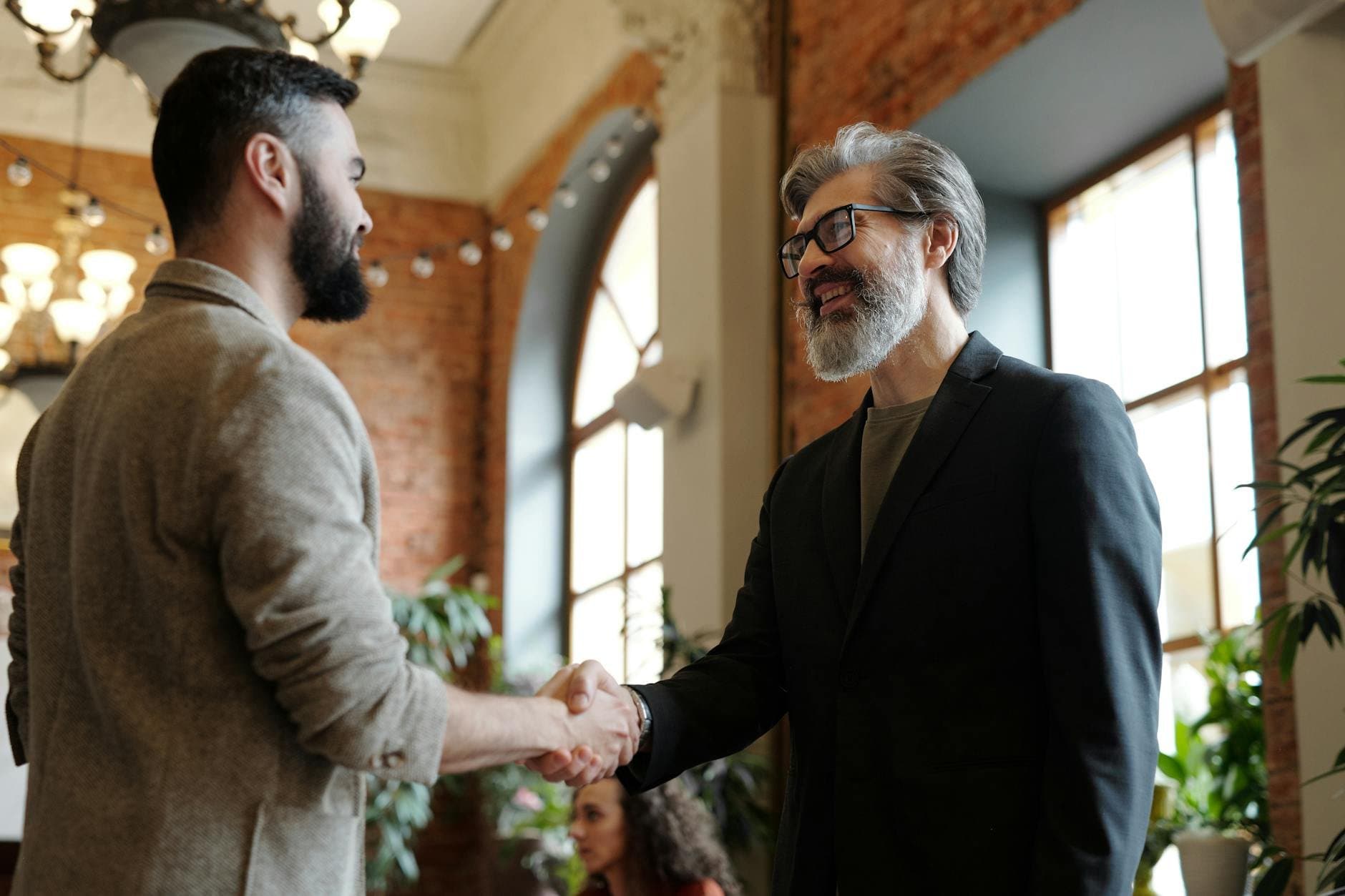 business professionals shaking hands in a modern office (Pexels)